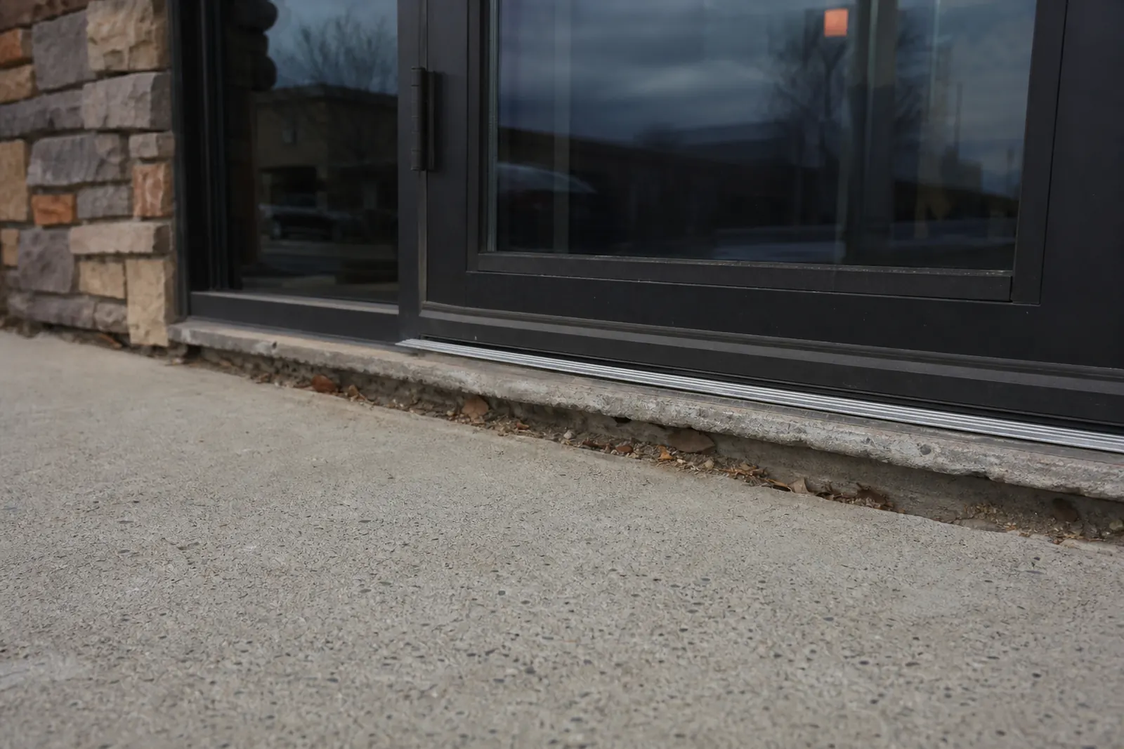 Concrete slab dropped below the threshold of a commercial glass door