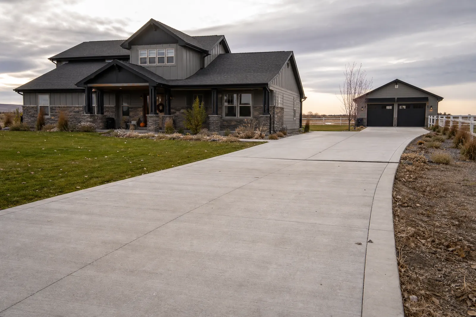 Long concrete driveway leading to a house and detached shop on acreage