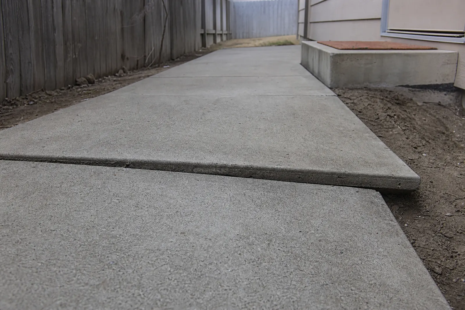 Side-yard walkway panel sunk well below the slab next to it