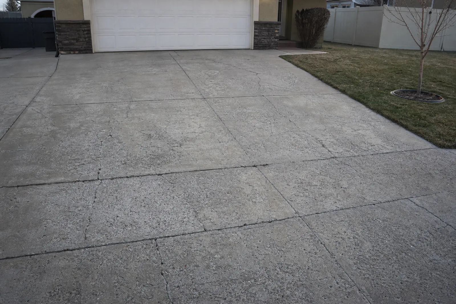 Weathered driveway with worn, scaled concrete in front of a garage